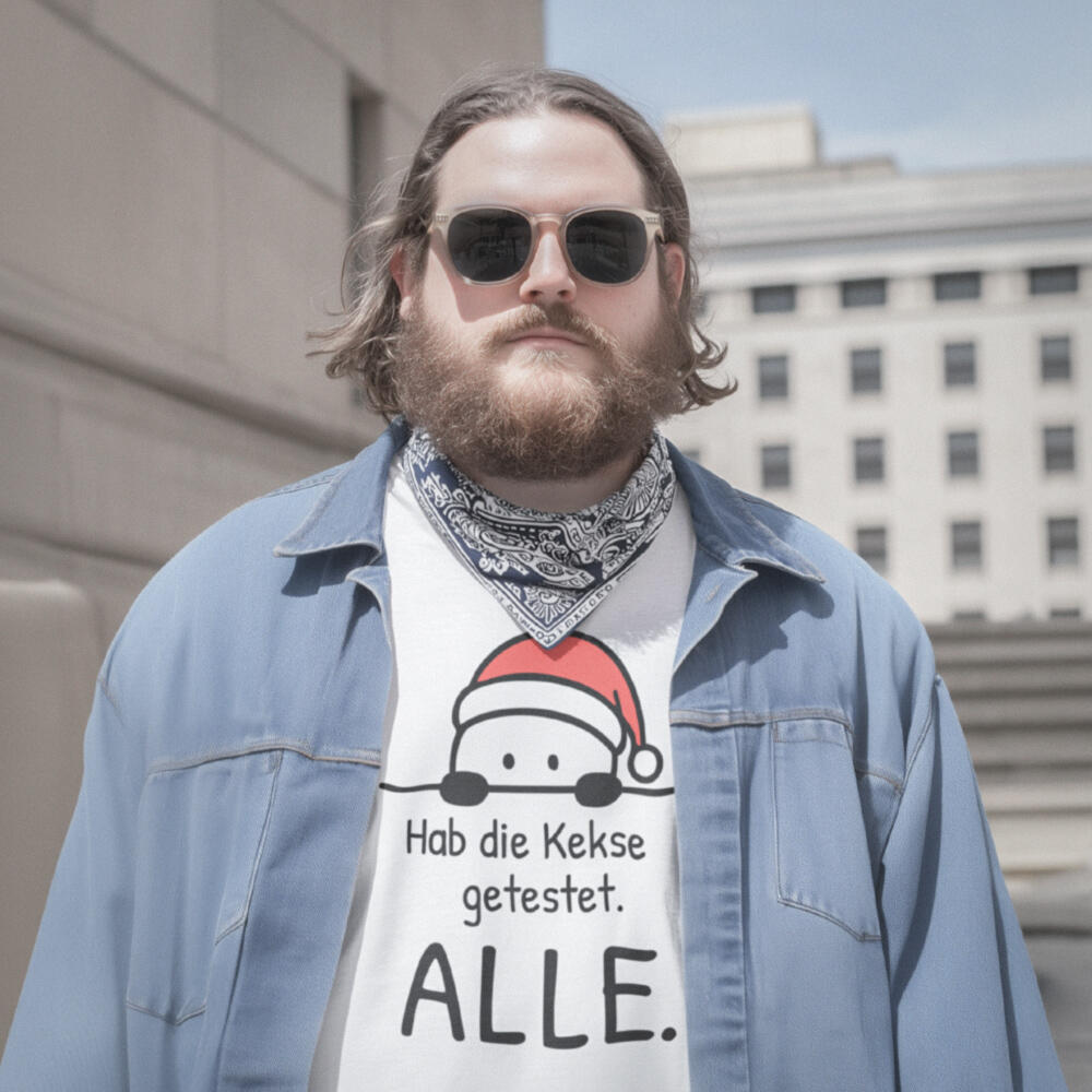 Foto eines übergewichtigen, bärtigen Mannes mit Sonnenbrille und offenem Jeanshemd und darunter weißem Weihnachtsshirt in ruhiger Straßenszene. Auf dem Shirt ist der Aufdruck einer kleinen Weihnachtsfigur mit dem Spruch „Hab die Kekse getestet. ALLE.“